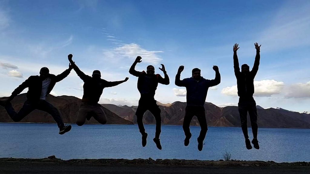 Group of Travelers jumping and celebrating near the lake.