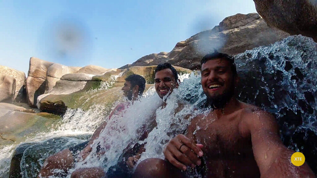 3 people sitting under the Hampi Waterfall