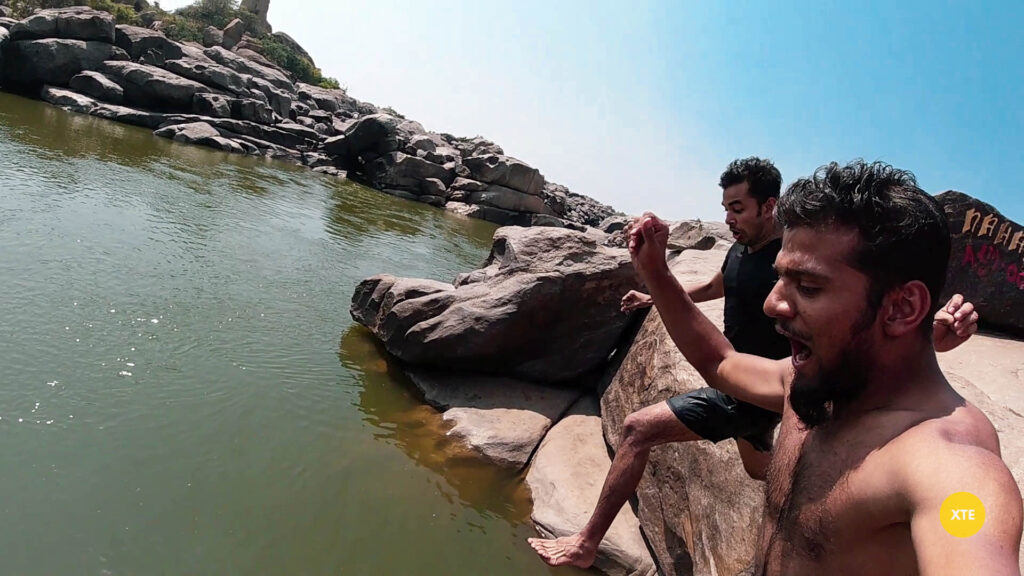 2 people Jumping off a cliff at a pond near Hampi Waterfalls