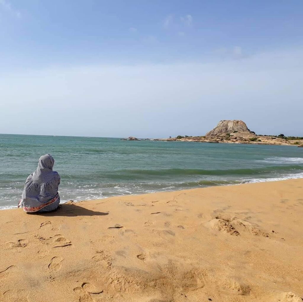 A person sitting on the shore of a beach at Yala National Park