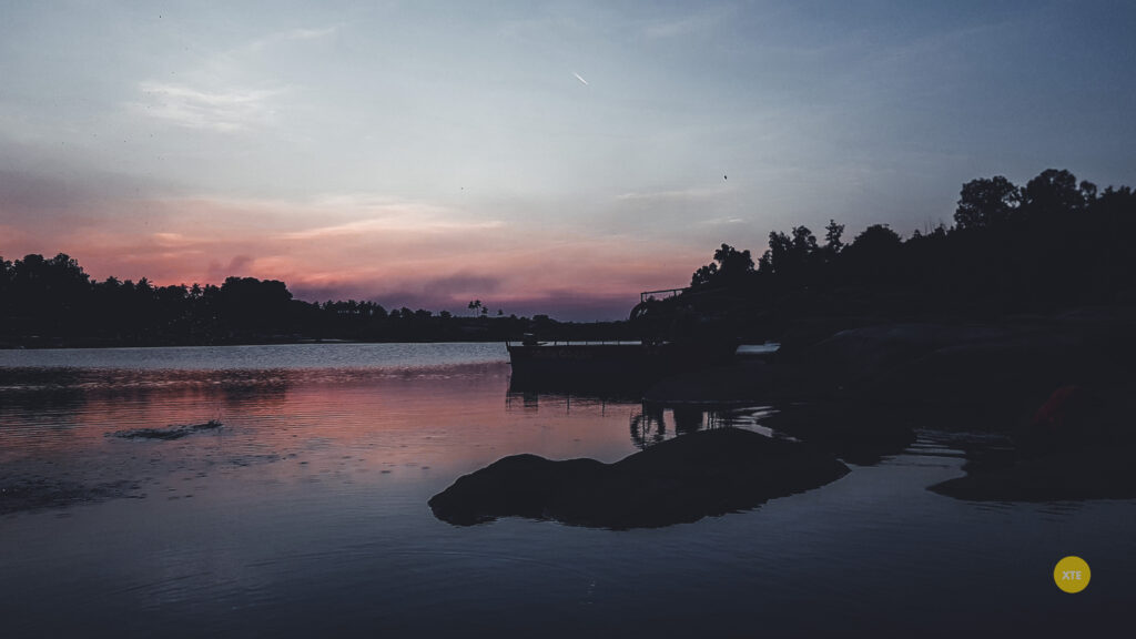 A sunset image of ferry point of Hampi Hippie Island with a contrail in the sky