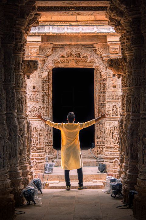 a person standing under the hanging arch and the pillars of sun temple in modhera gujarat